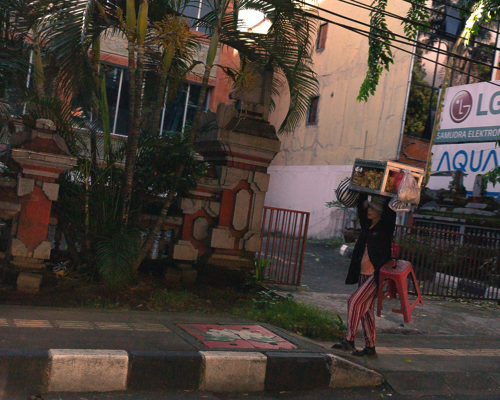 A street vendor carrying goods on her head at twilight in Bali