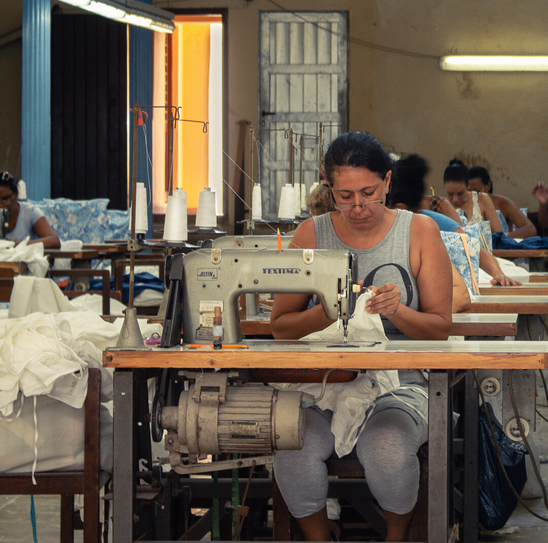 A woman working at a sewing machine in a textile workshop in Cuba